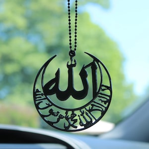 قلادة سوداء معلقة على مرآة السيارة تحمل اسم الله والشهادة